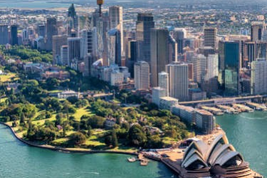 Sydney Opera House with Sydney Tower and city skyline in the background, Sydney Harbour and a boat cruising in the foreground.
